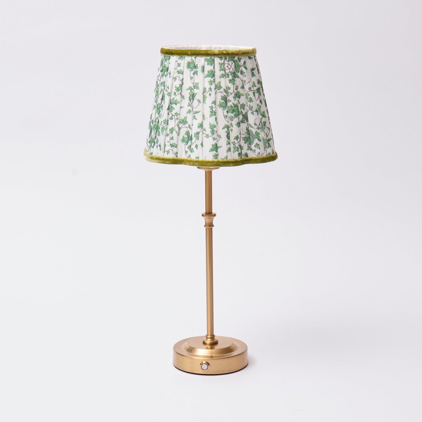 Table lamp with a green floral patterned shade on a white background